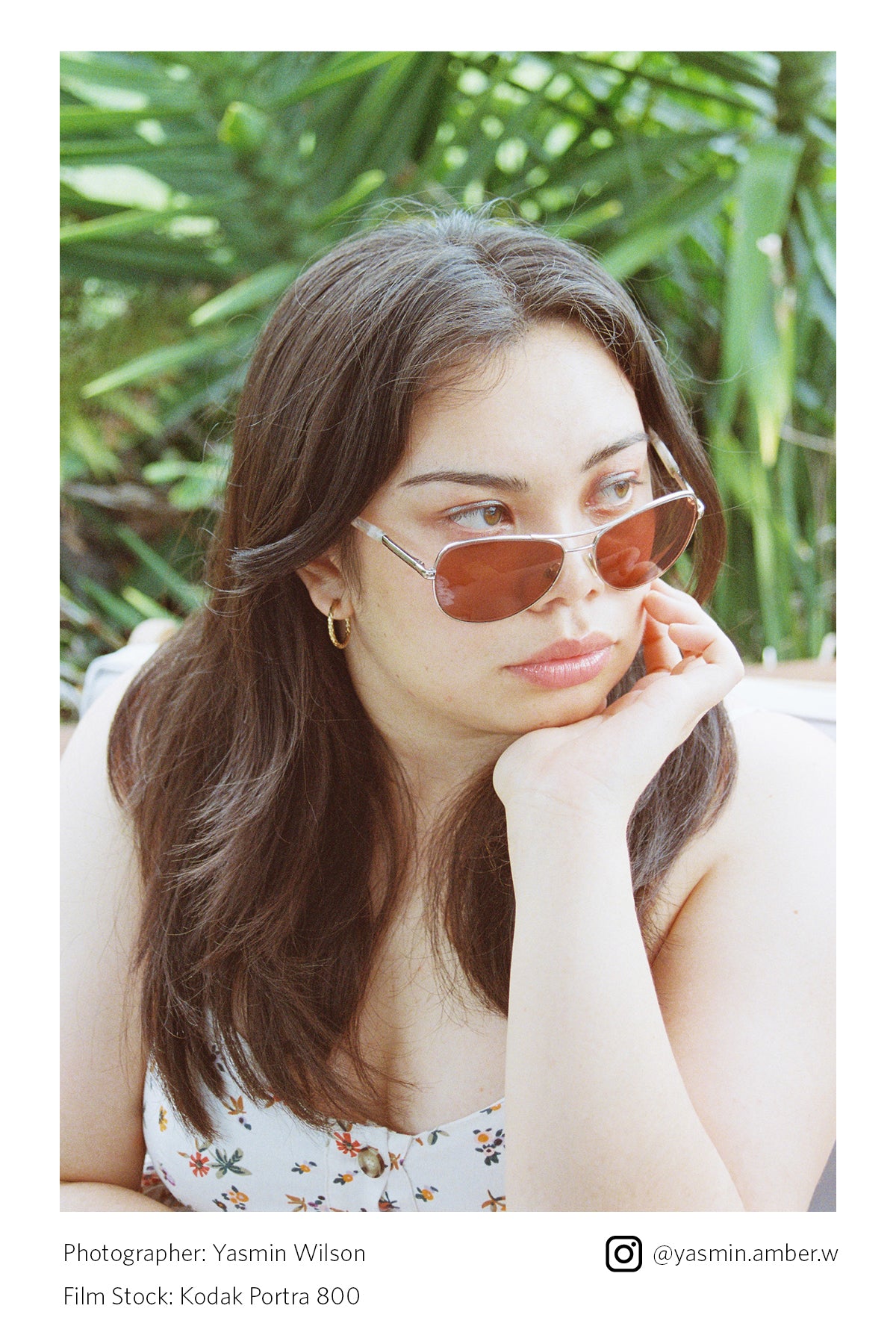 Woman wearing sunglasses with a blurred green foliage background