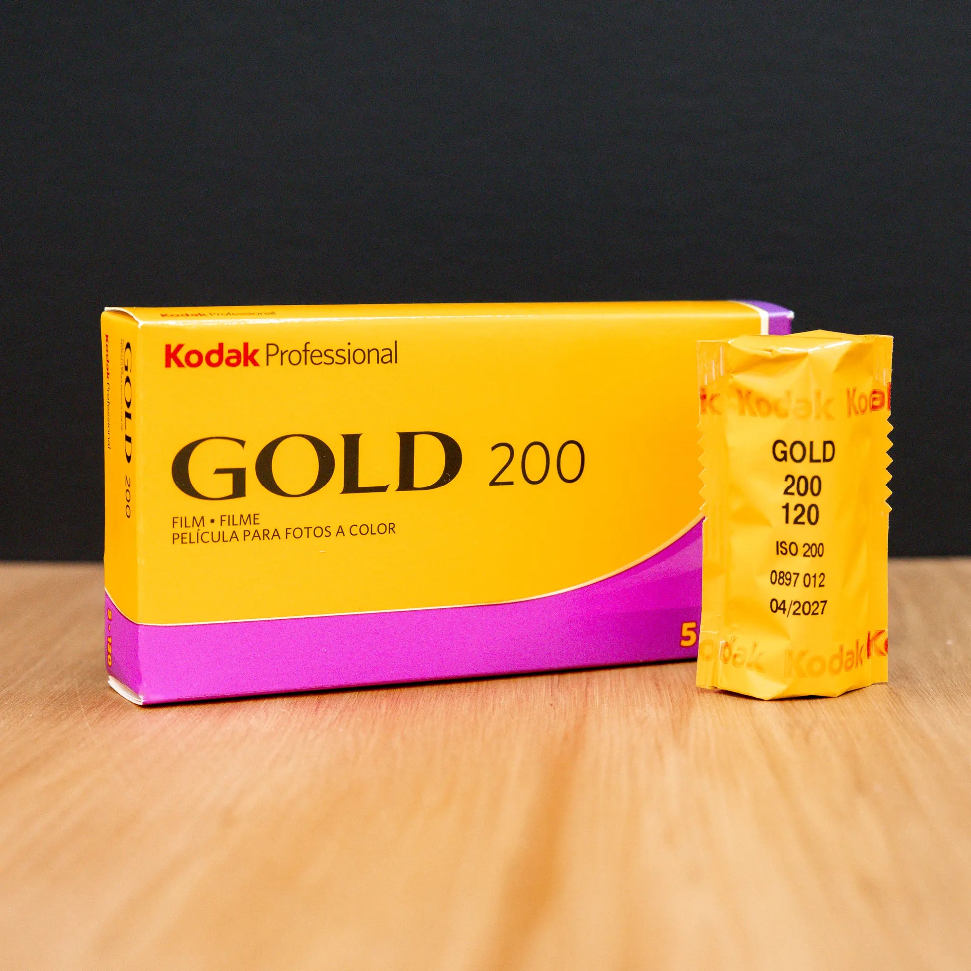 Kodak Gold 200 120 film packaging on a wooden surface with a black background