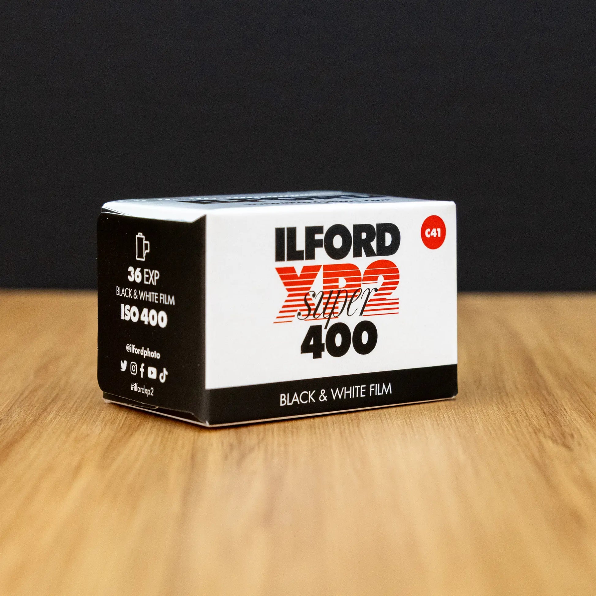 Ilford XP2 Super 400 black and white film box on a wooden surface with a dark background