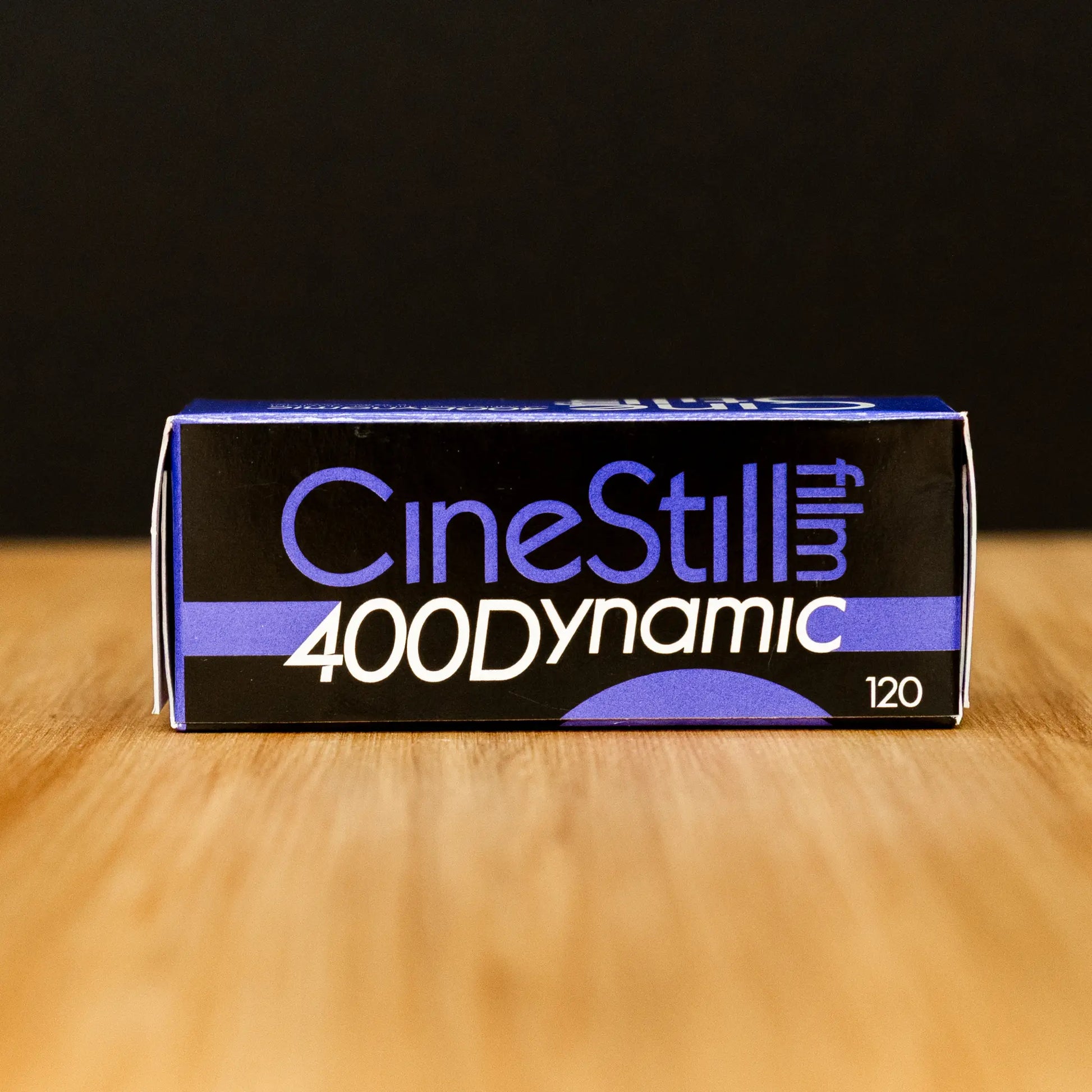 CineStill 400 Dynamic film packaging on a wooden surface with a black background