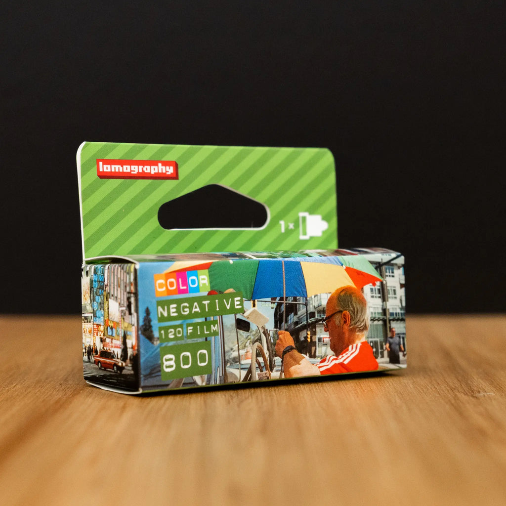 Lomography 800 film packaging on a wooden surface with a black background
