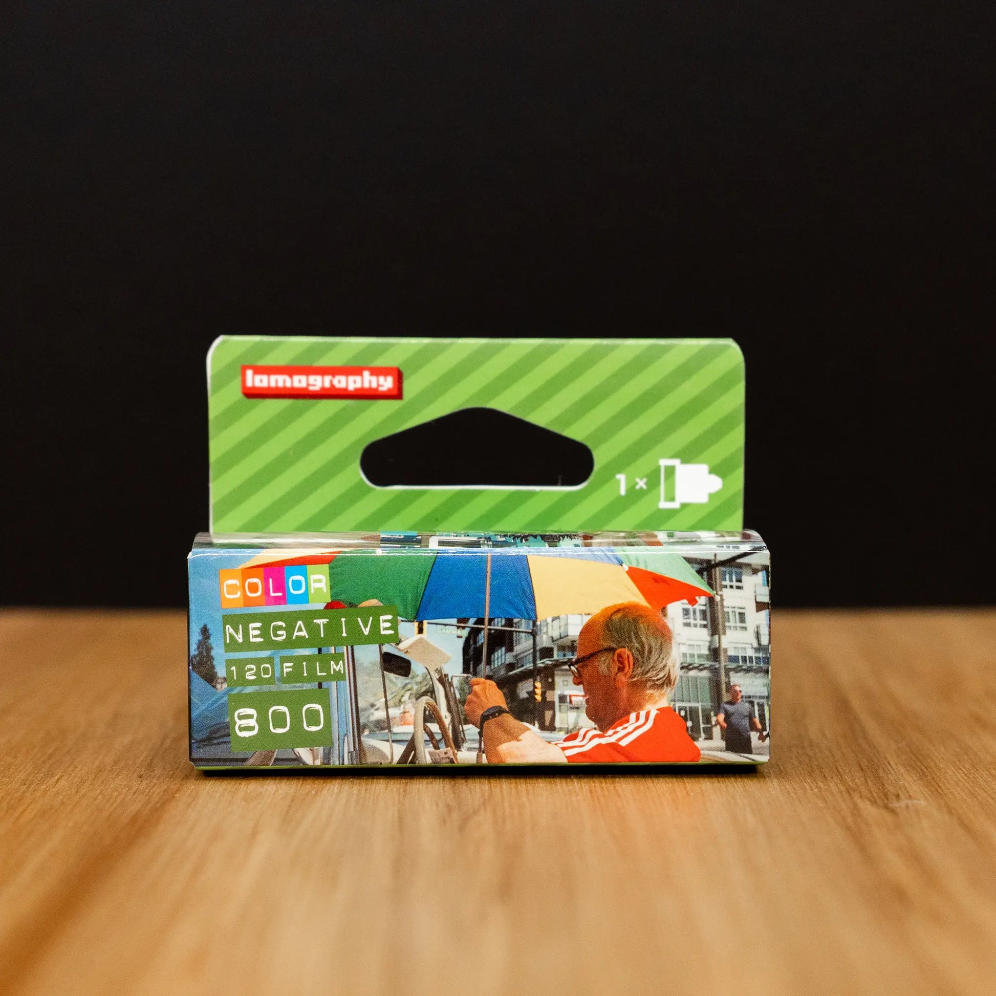 Lomography 800 film cartridge packaging on a wooden surface with a black background