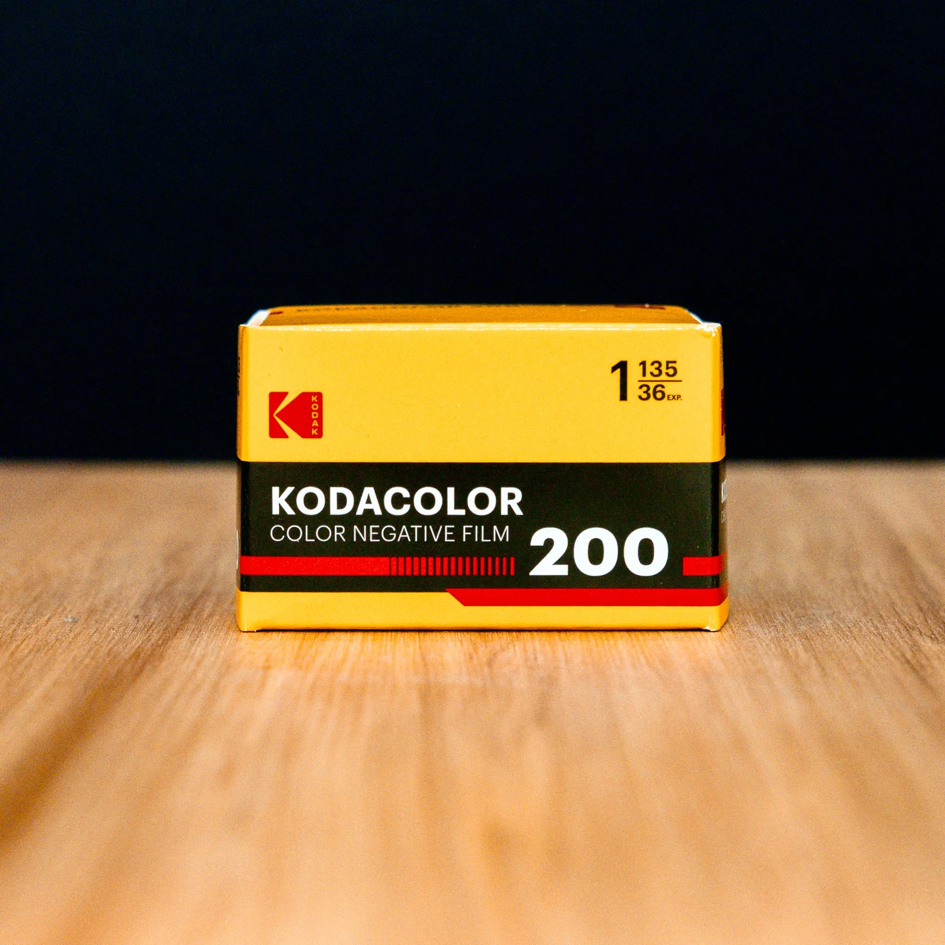 Kodacolor color negative film canister on a wooden surface with a black background