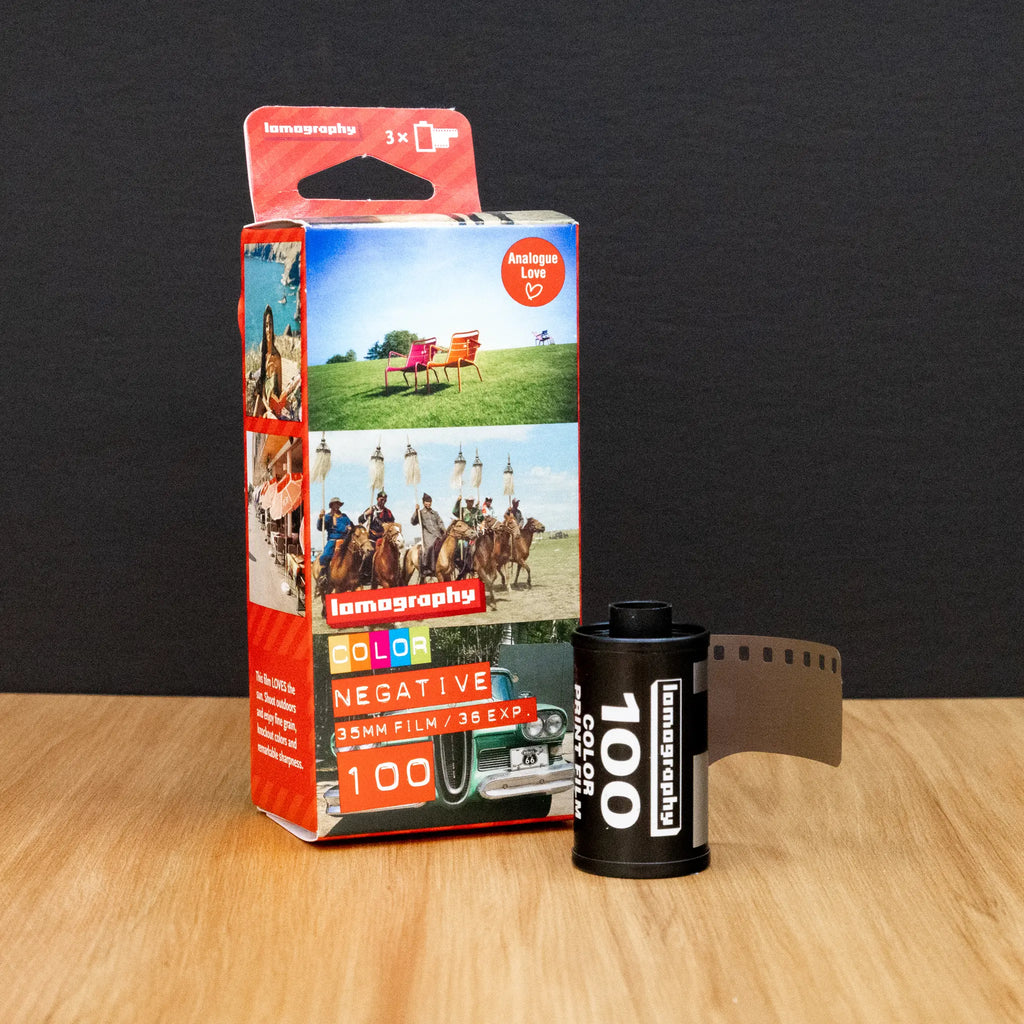 Lomography film canister and packaging on a wooden surface with a dark background