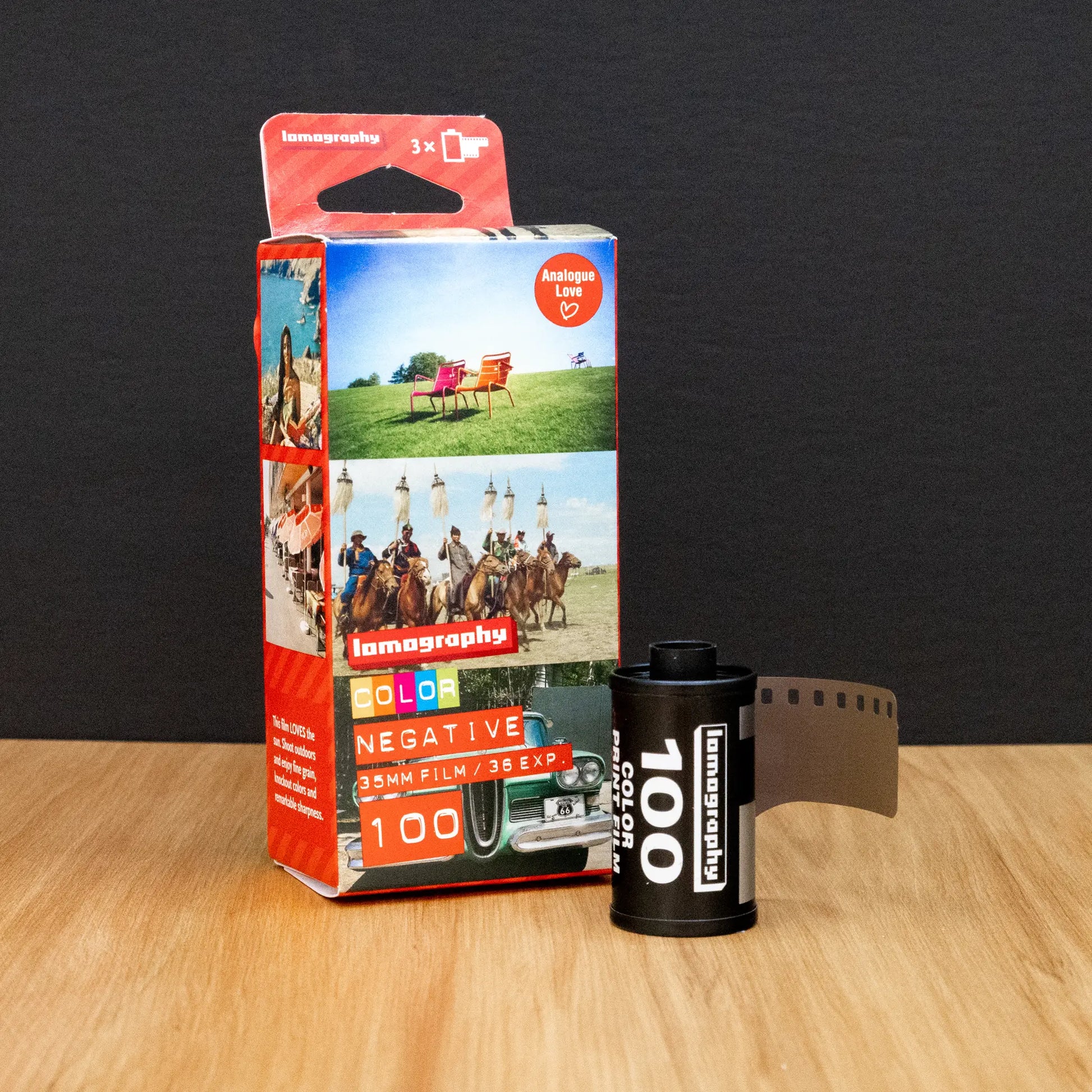 Lomography film canister and packaging on a wooden surface with a dark background