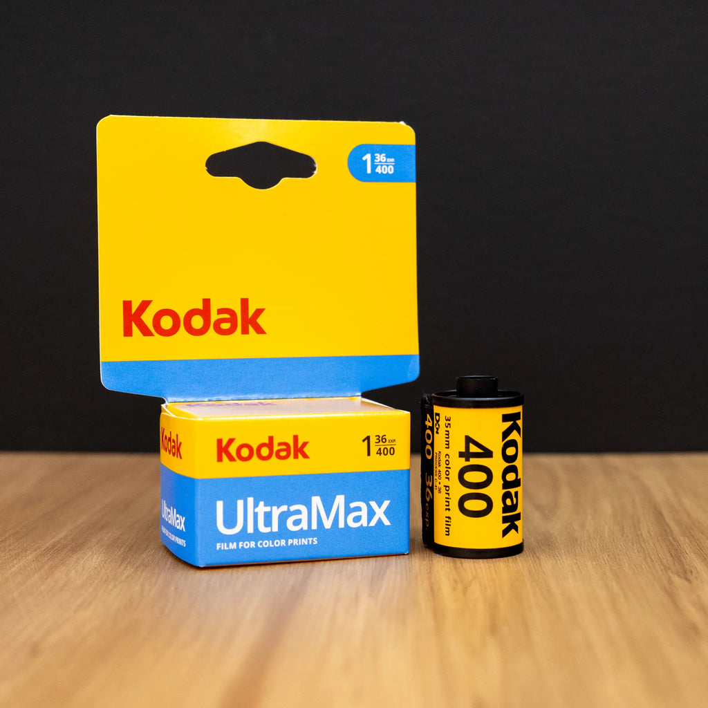 Kodak UltraMax and 400 film packaging on a wooden surface with a black background