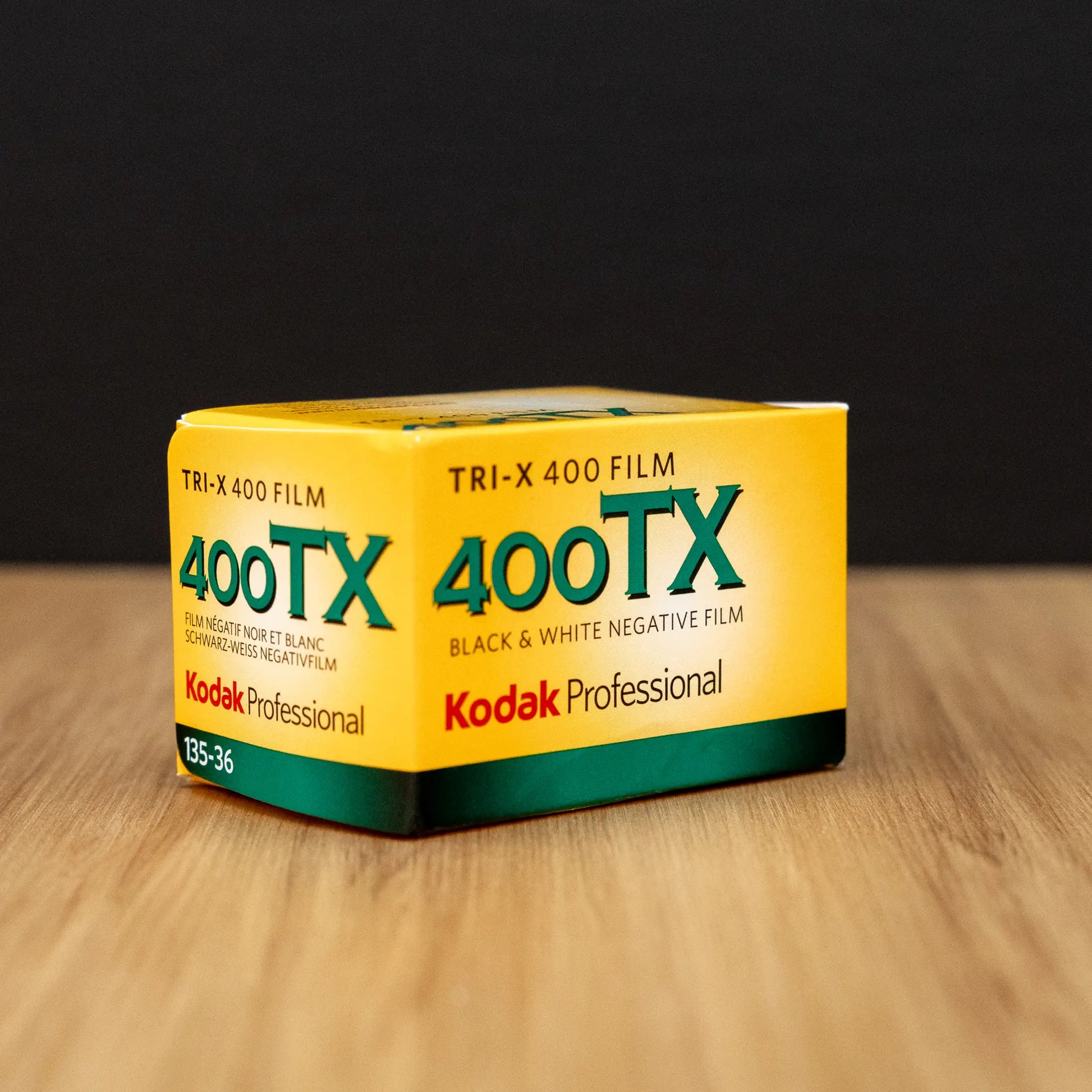 Kodak Professional Tri-X 400TX film box 3/4 view on a wooden surface with a black background