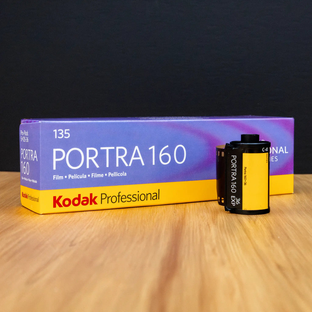 Kodak Professional Portra 160 film packaging on a wooden surface with a dark background