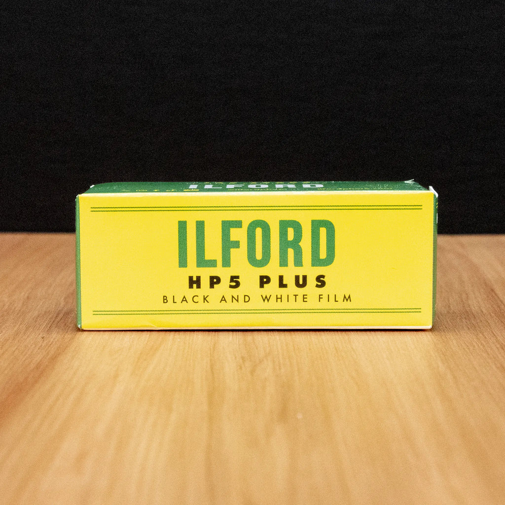 Ilford HP5 Plus black and white film limited edition box on a wooden surface with a dark background