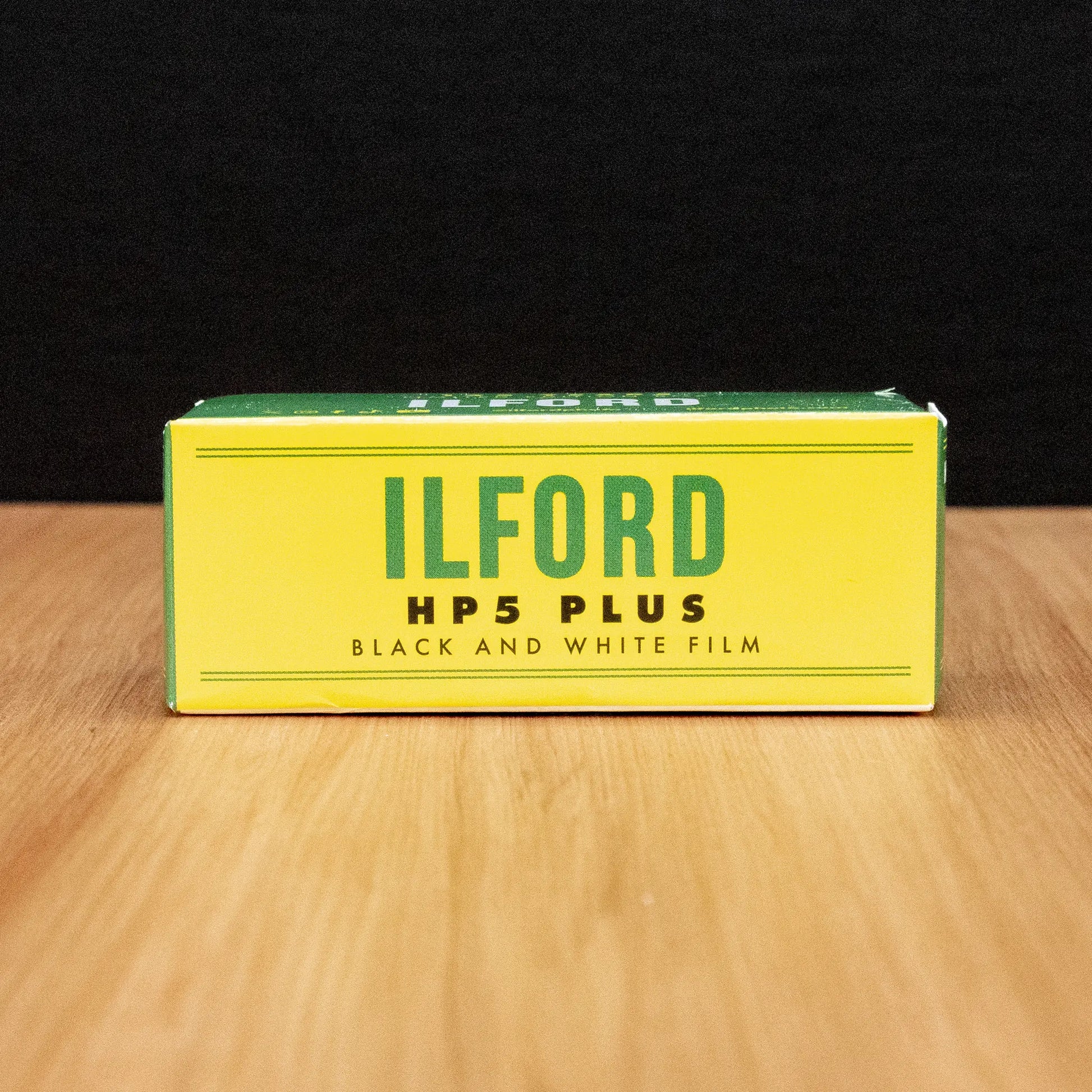 Ilford HP5 Plus black and white film limited edition box on a wooden surface with a dark background