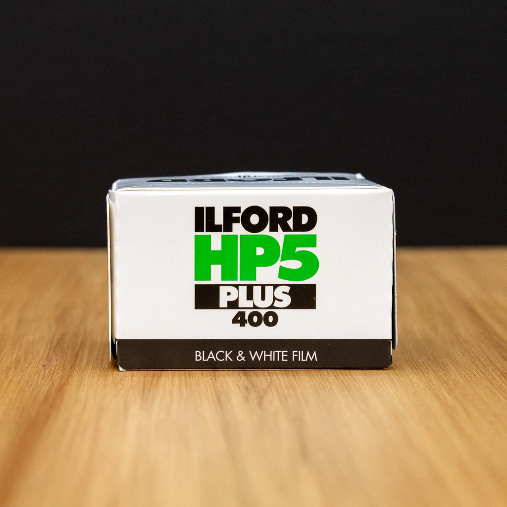 Ilford HP5 Plus 400 black and white film box on a wooden surface with a dark background