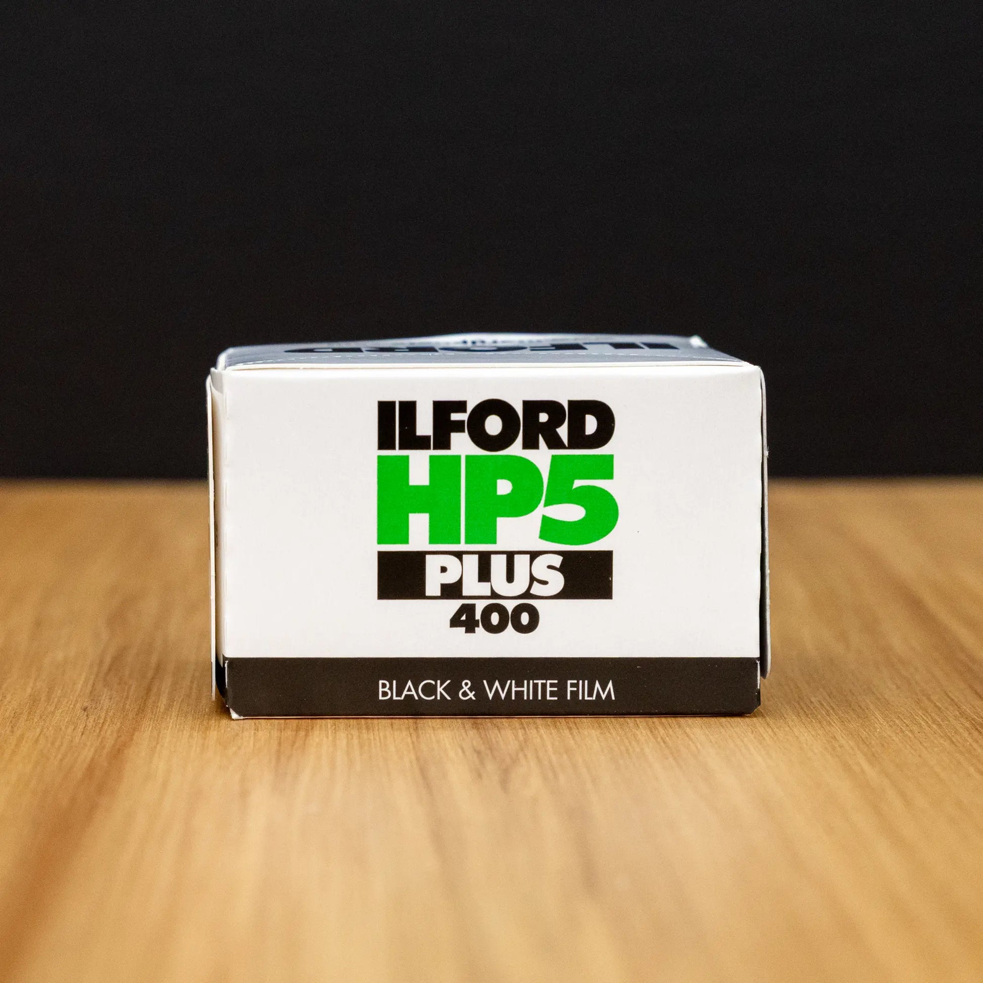 Ilford HP5 Plus 400 black and white film box on a wooden surface with a dark background