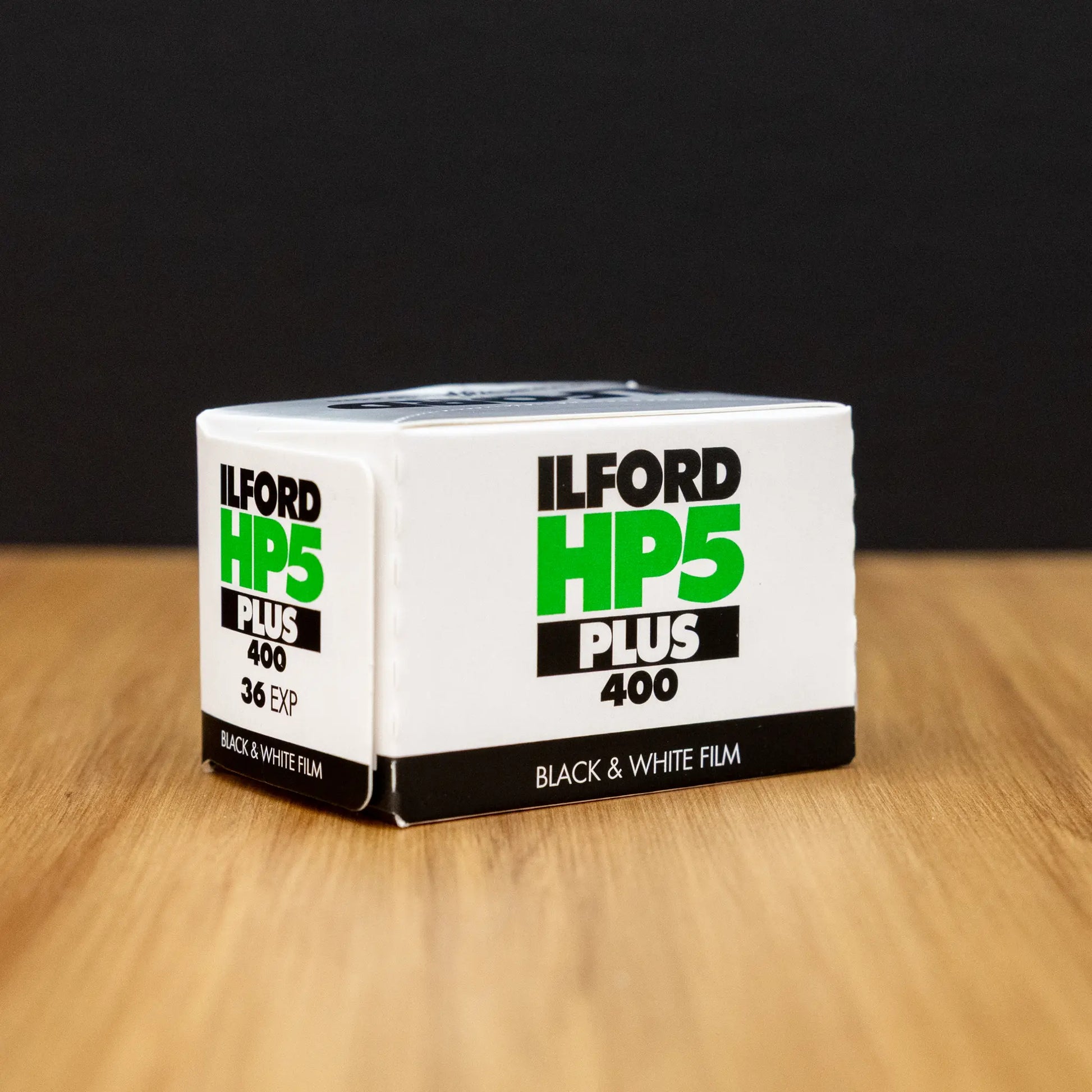 Ilford HP5 Plus 400 black and white film box 3/4 view on a wooden surface with a dark background