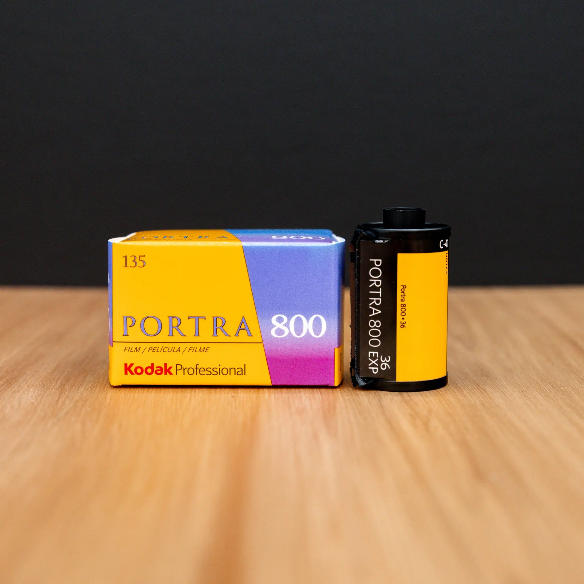 Kodak Portra 800 film canister and packaging on a wooden surface with a black background