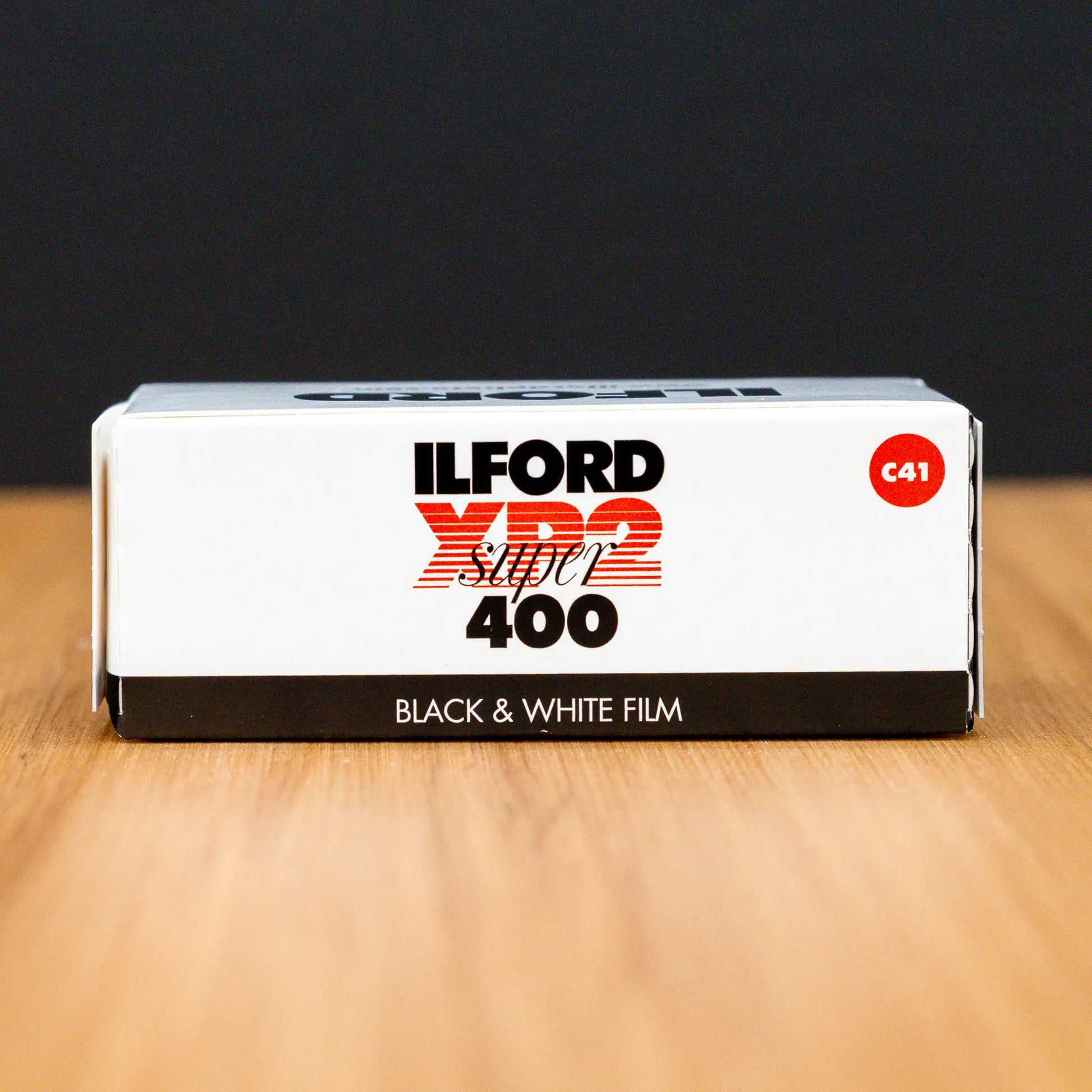 Ilford XP2 400 speed 120 black and white film box on a wooden surface with a dark background