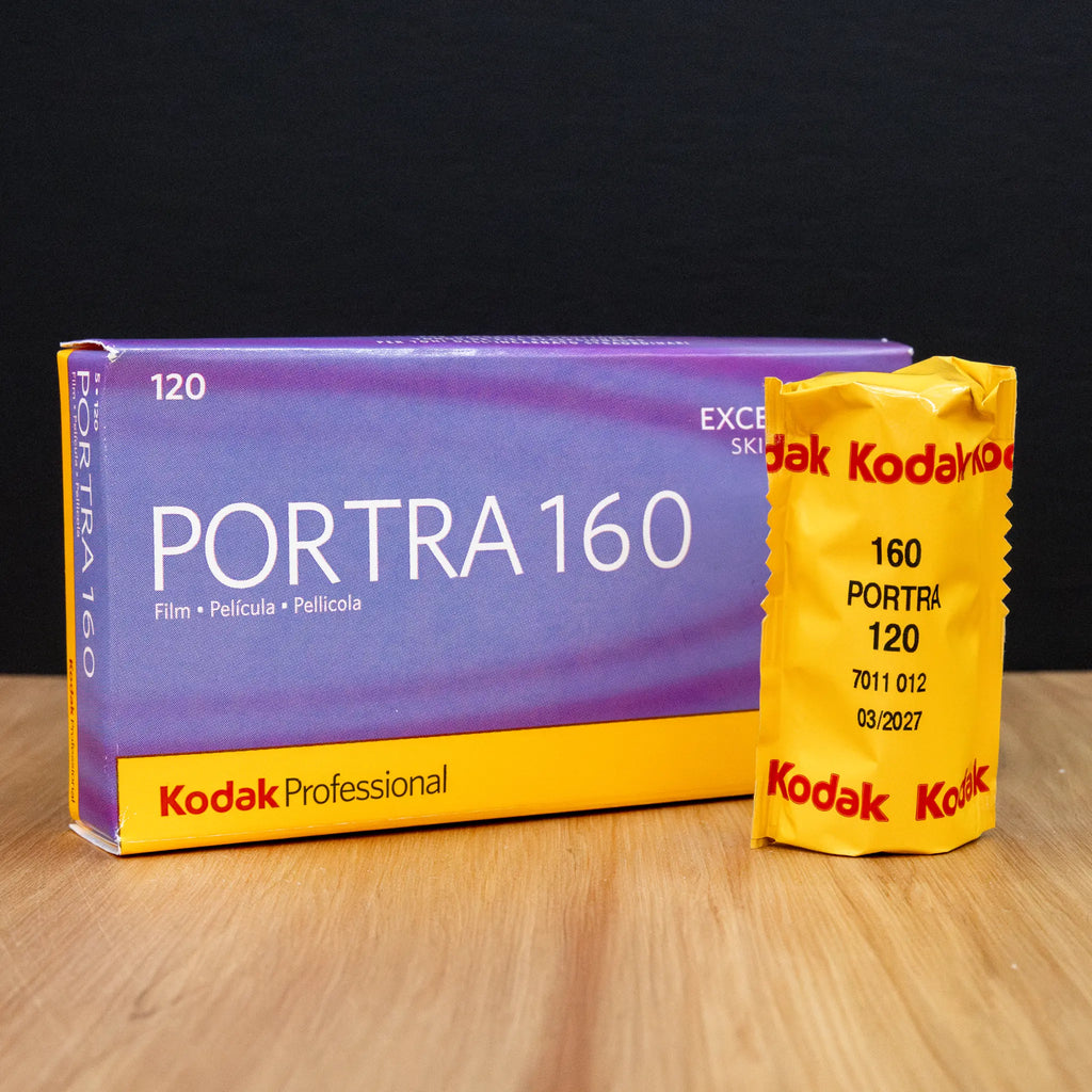 Kodak Portra 160 120 film packaging on a wooden surface with a dark background