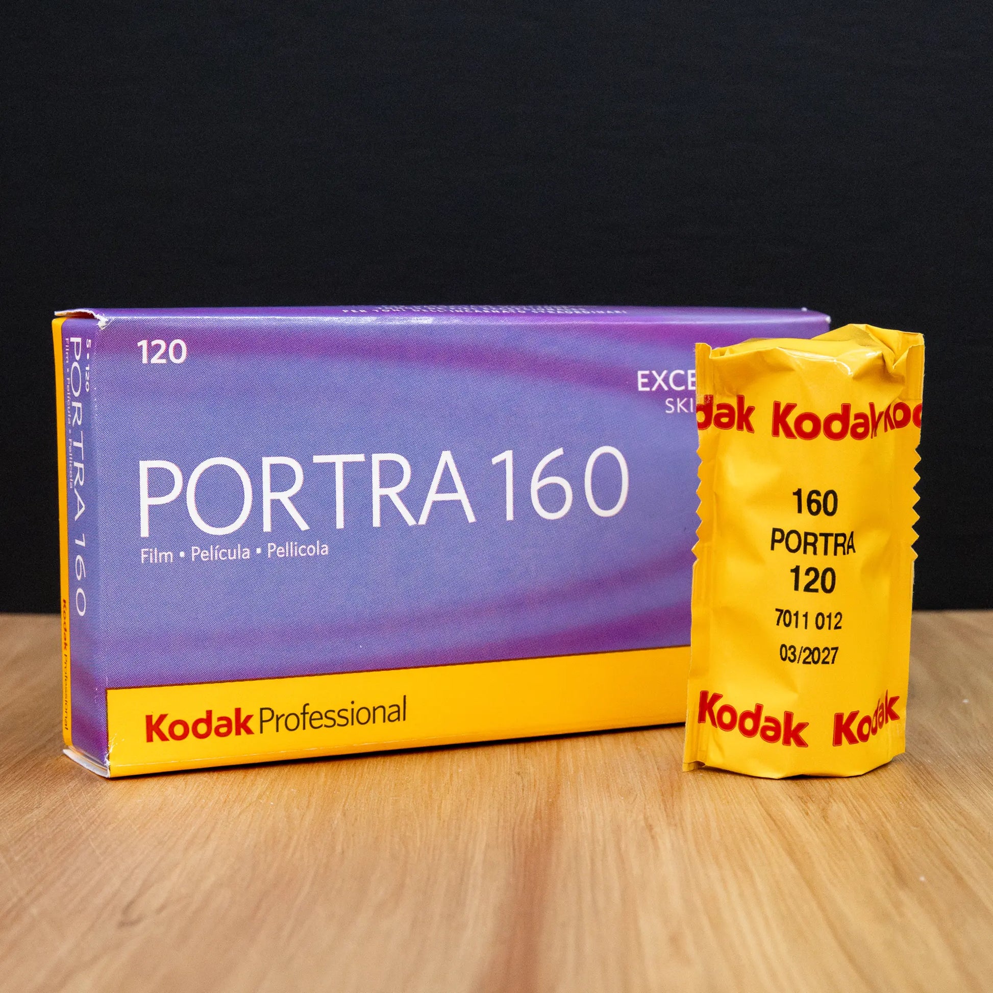 Kodak Portra 160 120 film packaging on a wooden surface with a dark background
