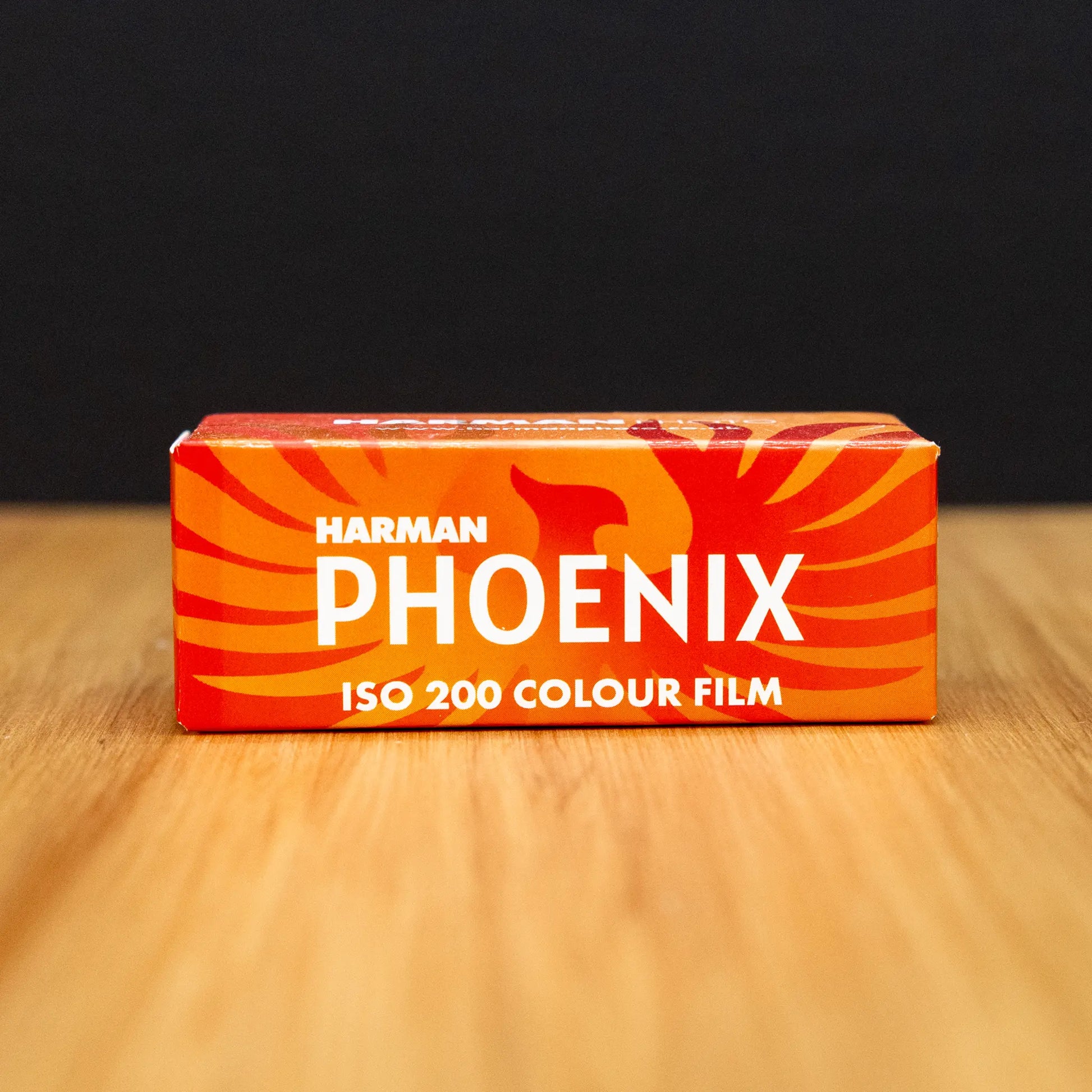 Harman Phoenix 120 Iso 200 colour film box sitting on a wooden surface with black background
