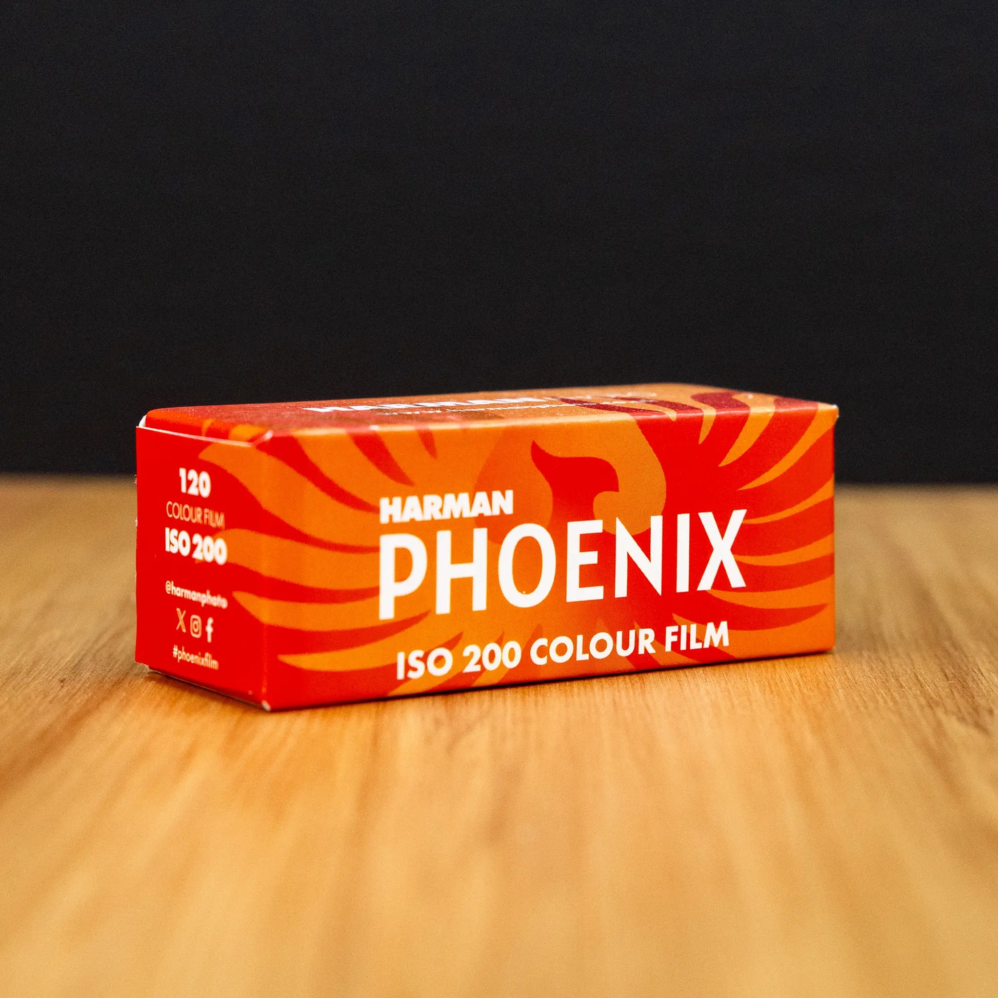 Harmarn Phoenix ISO 200 color film box 3/4 view on a wooden surface with a black background