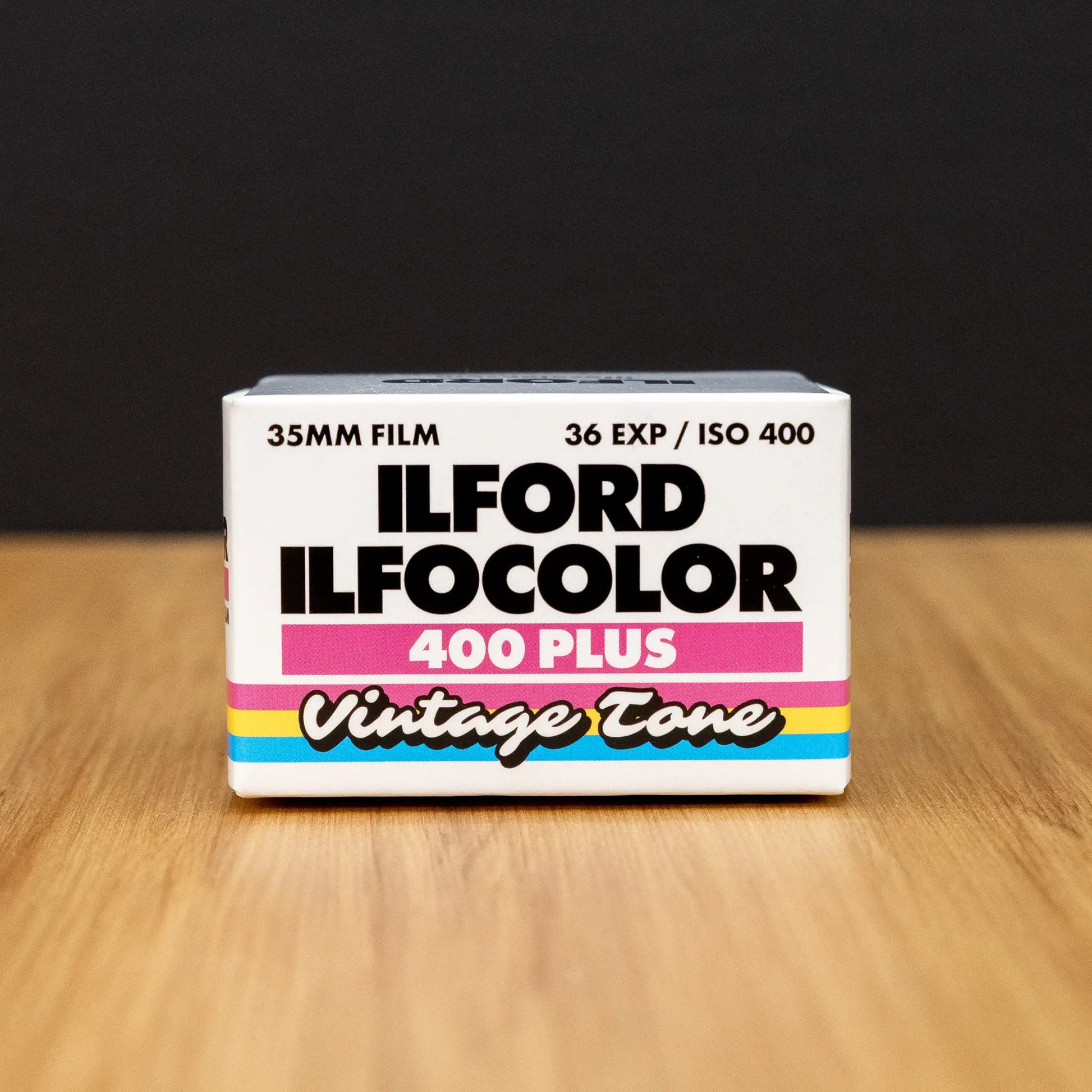 Ilford Ilfocolor 400 Plus vintage tone film box on a wooden surface with a black background