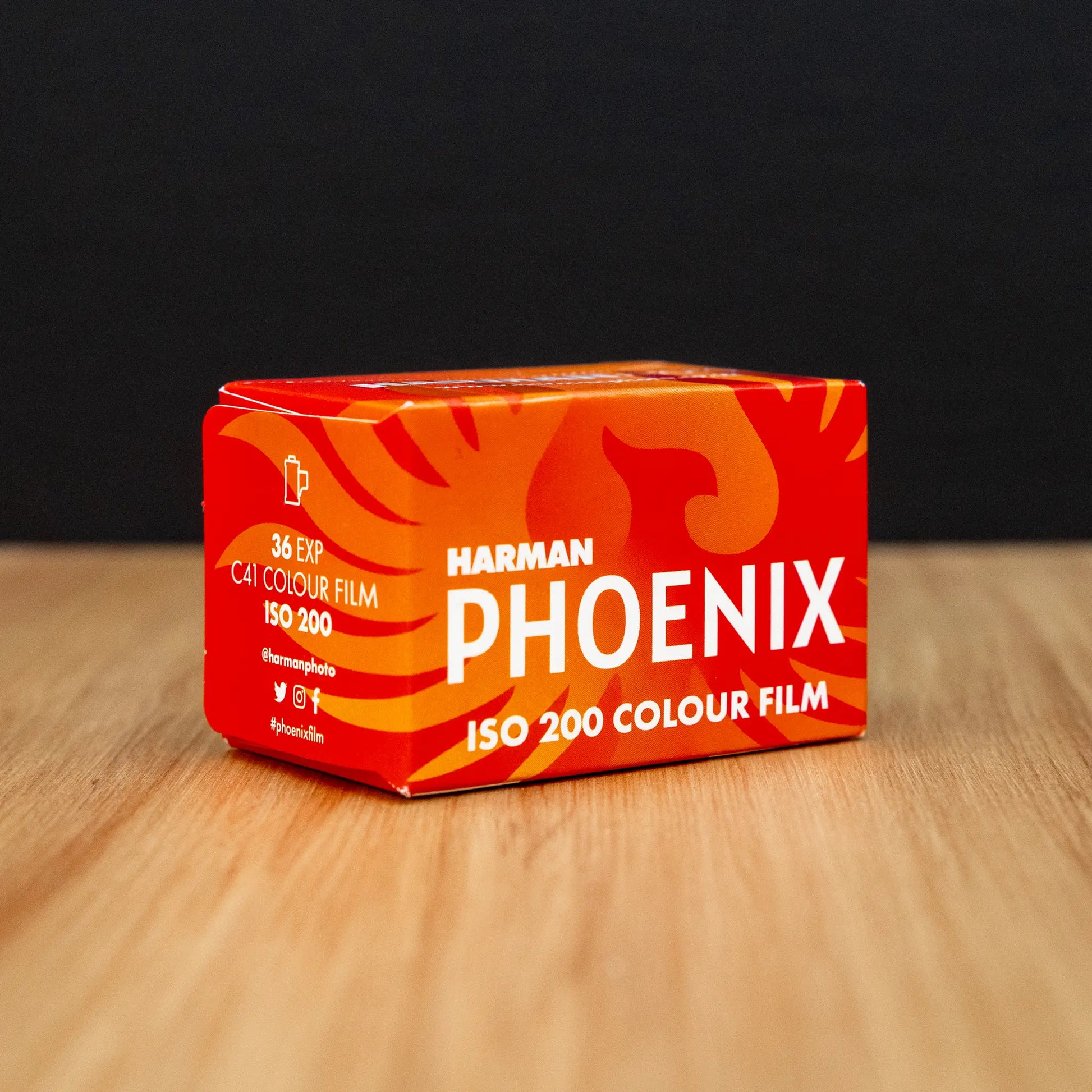 Harman Phoenix ISO 200 colour film box on a wooden surface with a black background