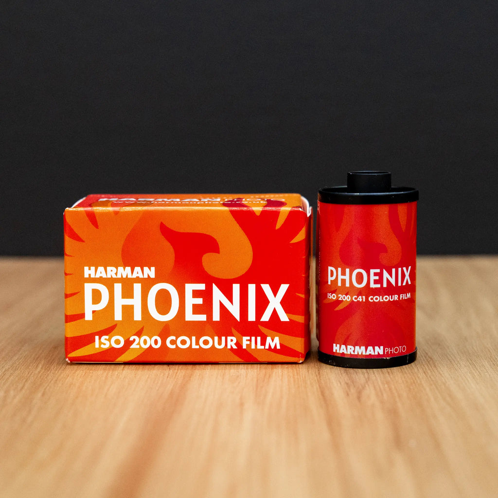 Harmen Phoenix ISO 200 color film packaging and film canister on a wooden surface with a black background