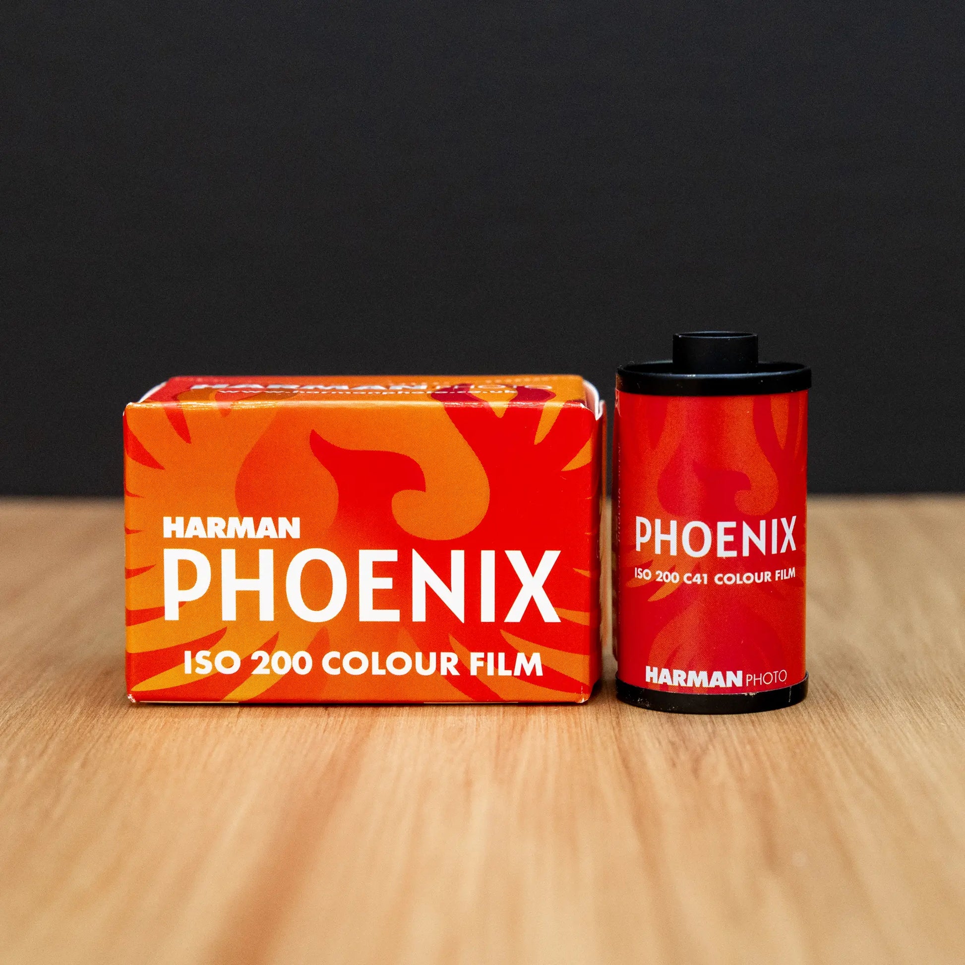 Harmen Phoenix ISO 200 color film packaging and film canister on a wooden surface with a black background