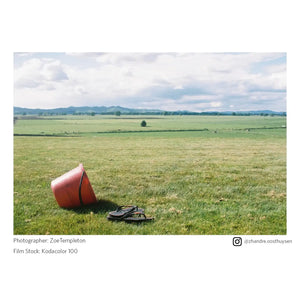 Red bucket on a grassy field with a scenic background