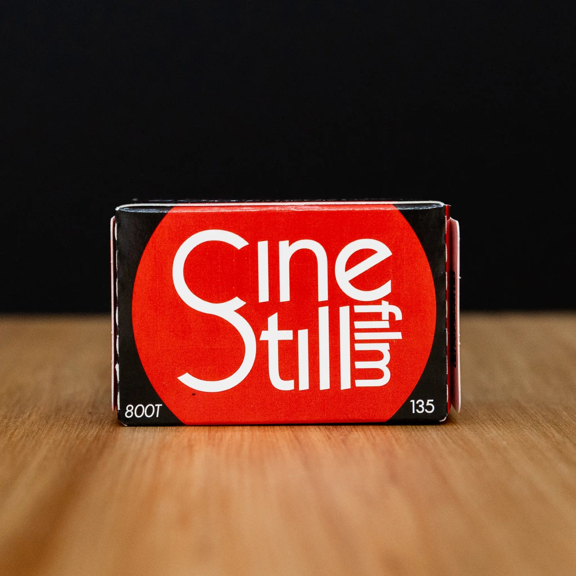 Cinestill film packaging on a wooden surface with a black background