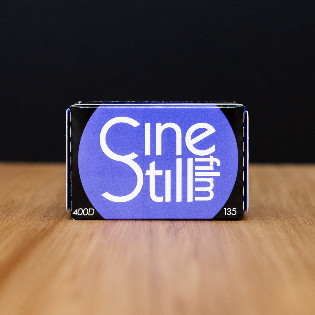 CineStill film packaging on a wooden surface with a black background