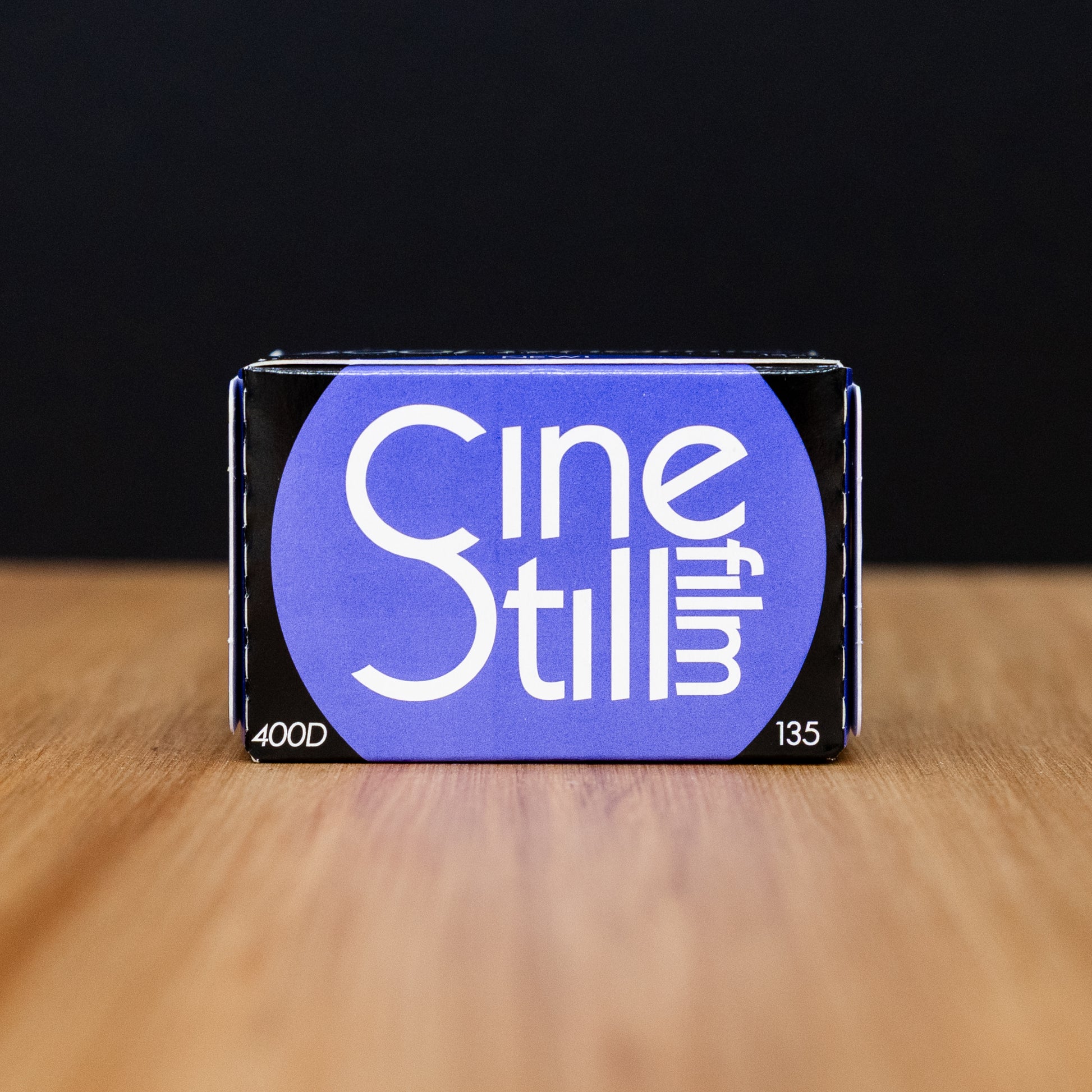 CineStill film packaging on a wooden surface with a black background