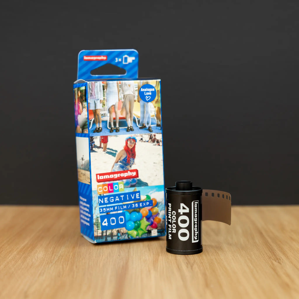 Lomography 400 film packaging and roll on a wooden surface with a dark background