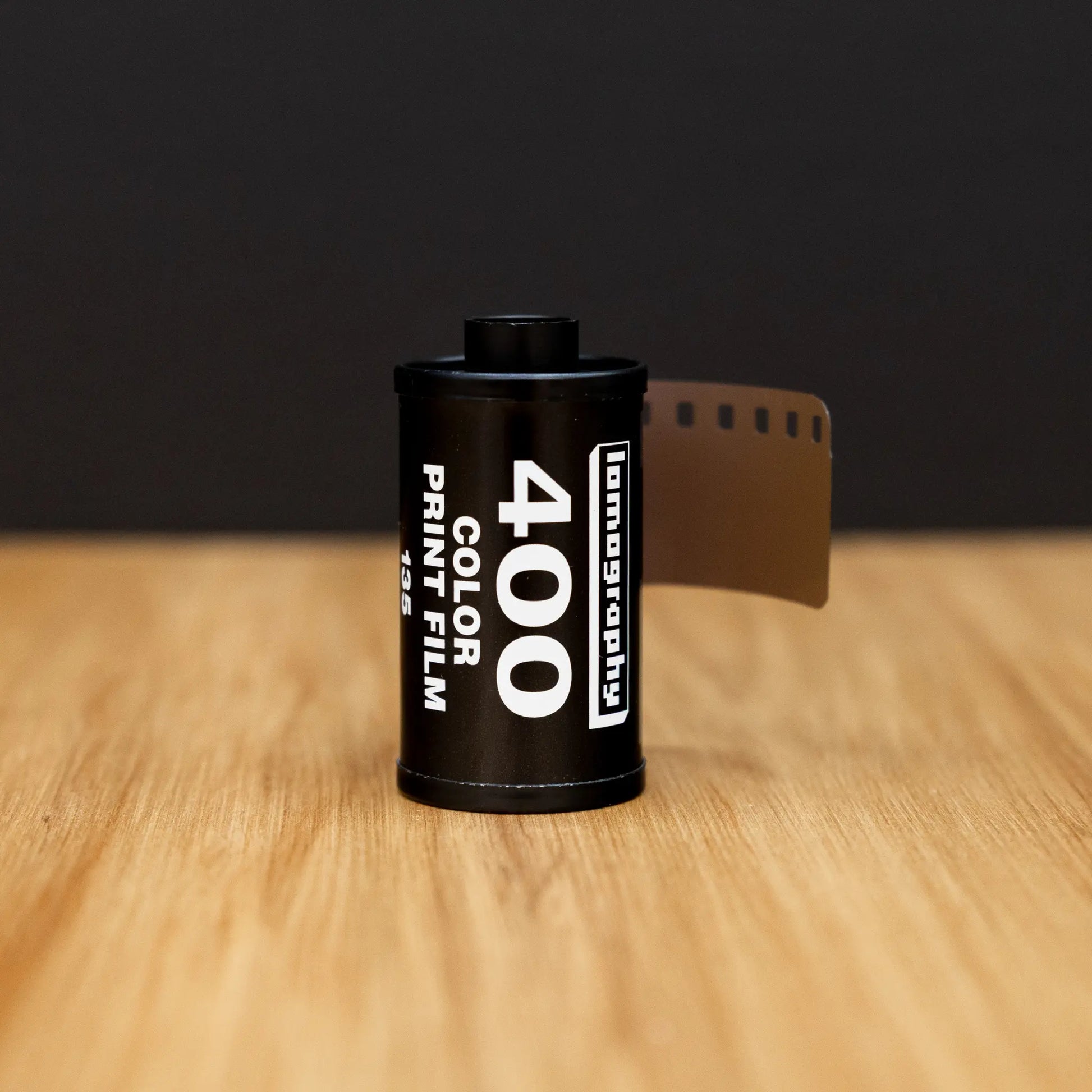 Film canister with 'Lomography' branding on a wooden surface