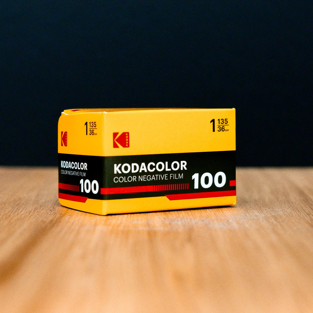 Kodacolor 100 film canister on a wooden surface with a dark background