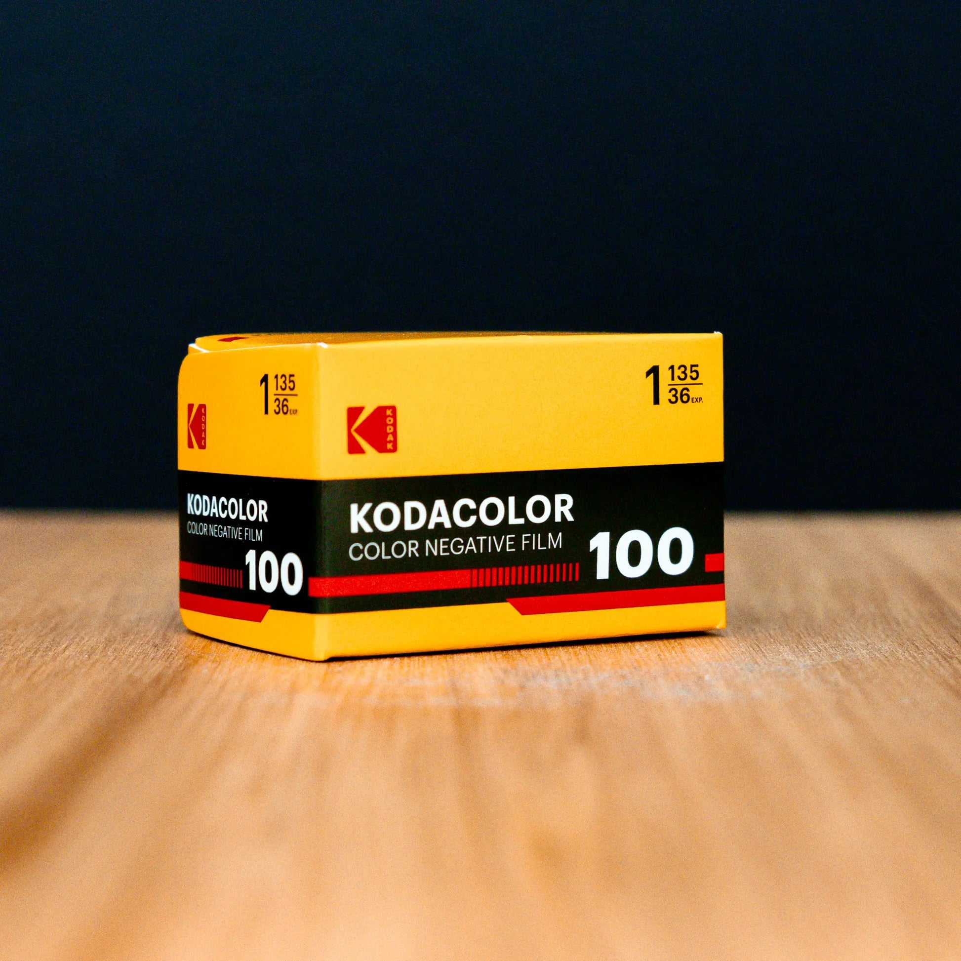 Kodacolor 100 film canister on a wooden surface with a dark background