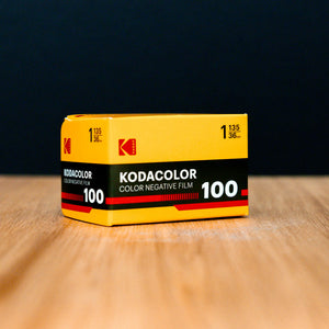 Kodacolor 100 film canister on a wooden surface with a dark background