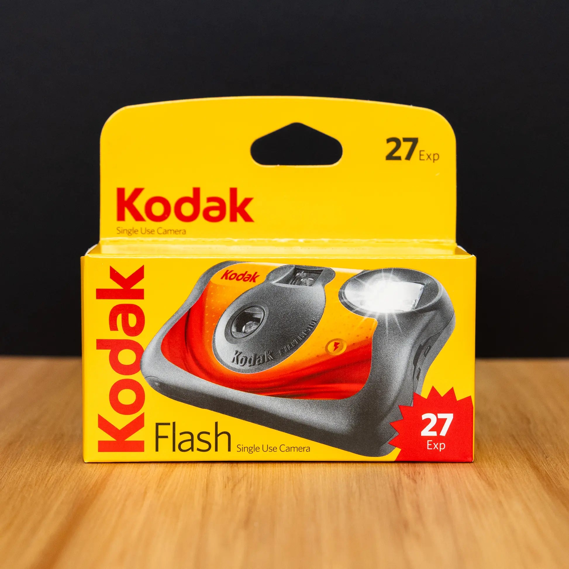 Kodak single-use camera packaging on a wooden surface with a black background