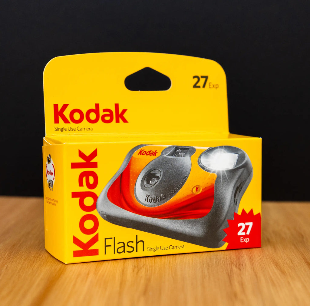 Kodak single-use camera packaging on a wooden surface with a black background